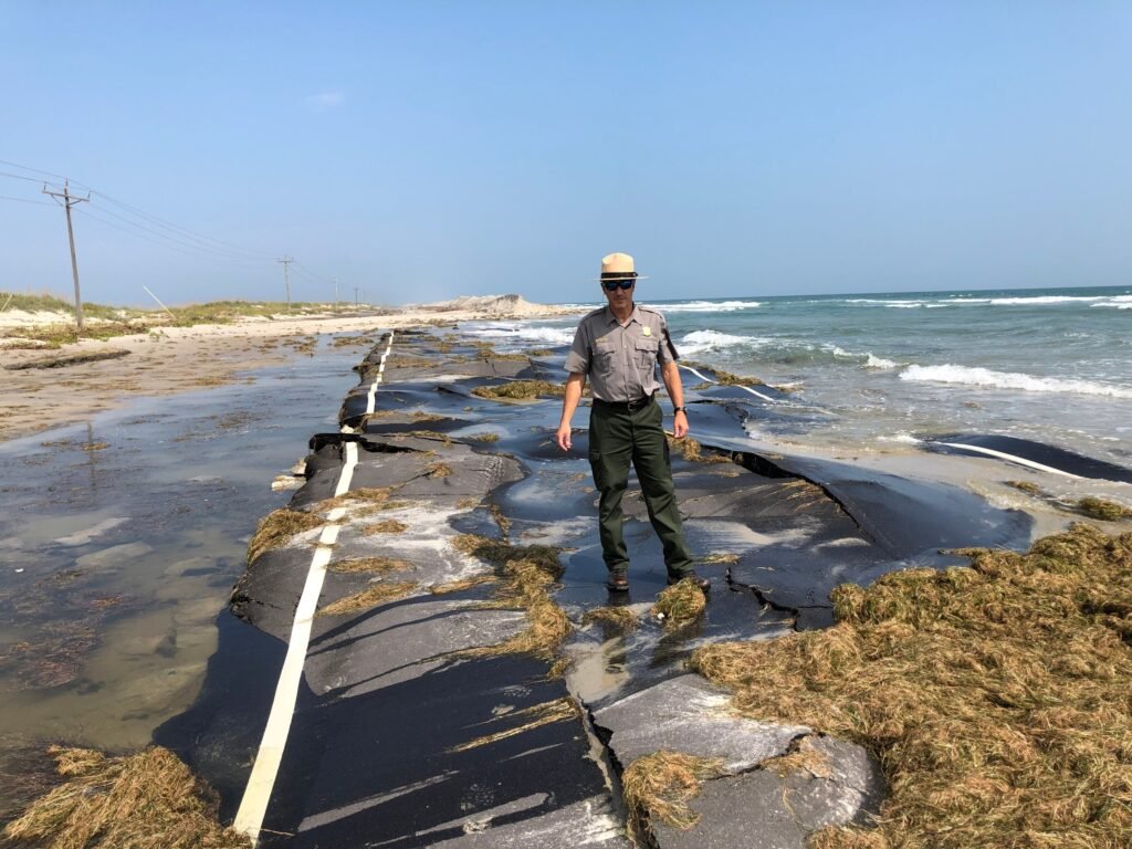 A National Park Service official inspecting storm damage and sand covering NC-12 on Ocracoke Island