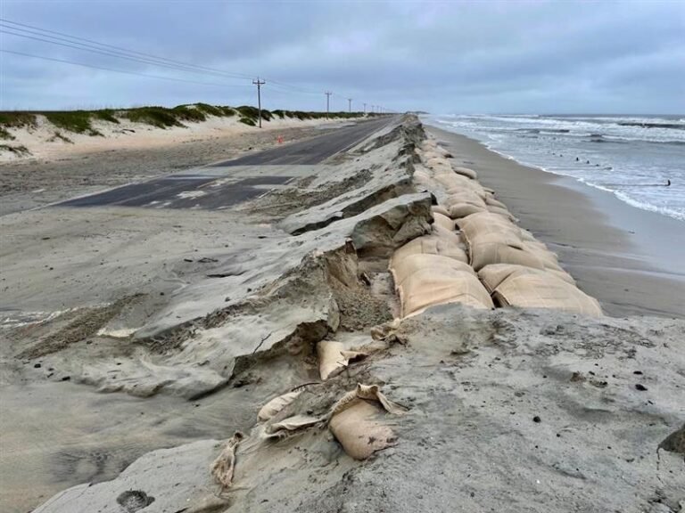 Sand and ocean water washing across NC Highway 12 at the sandbag dunes on the Outer Banks