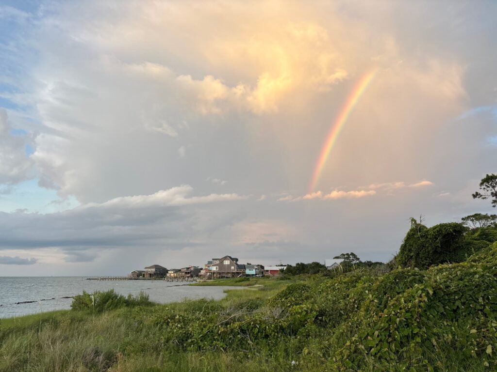 A rainbow arcing over Ocracoke Village at sunset with storm clouds behind